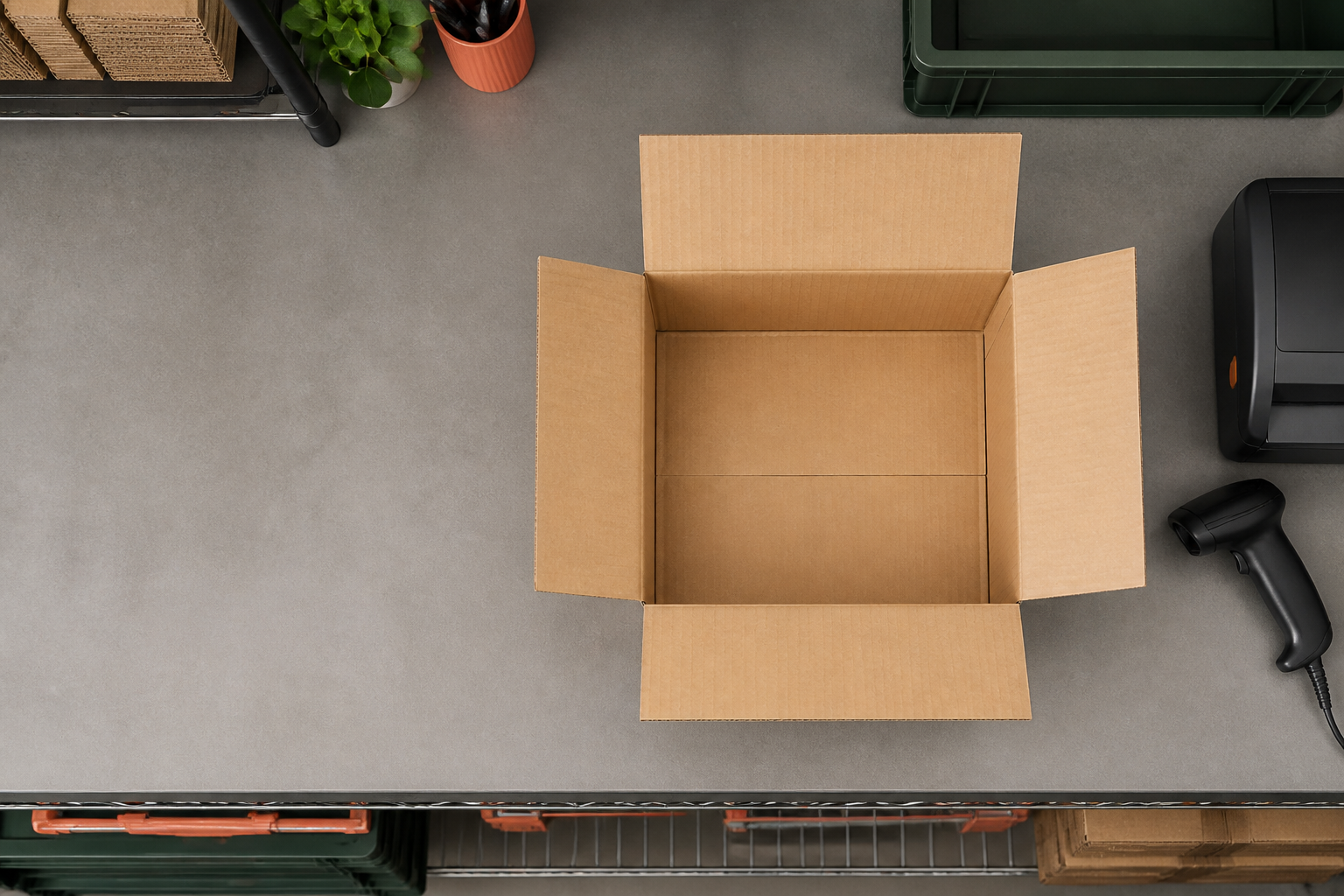 Top-down ecommerce packing station with an open cardboard box and barcode scanner